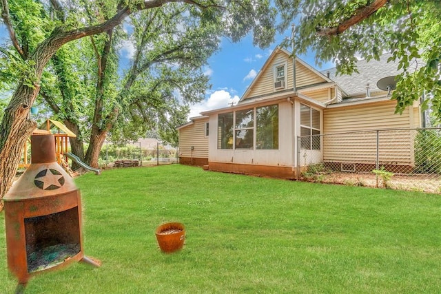 rear view of property with a lawn and a playground