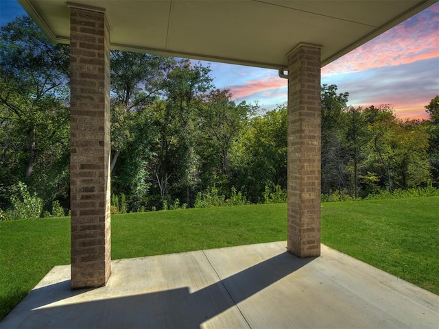 patio terrace at dusk featuring a lawn