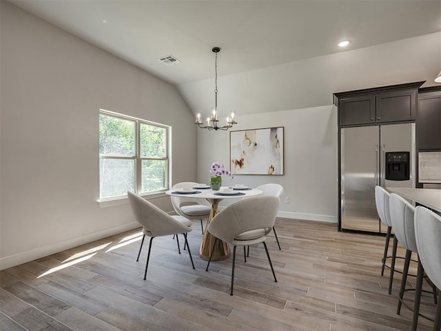 dining space with a chandelier, light hardwood / wood-style floors, and vaulted ceiling