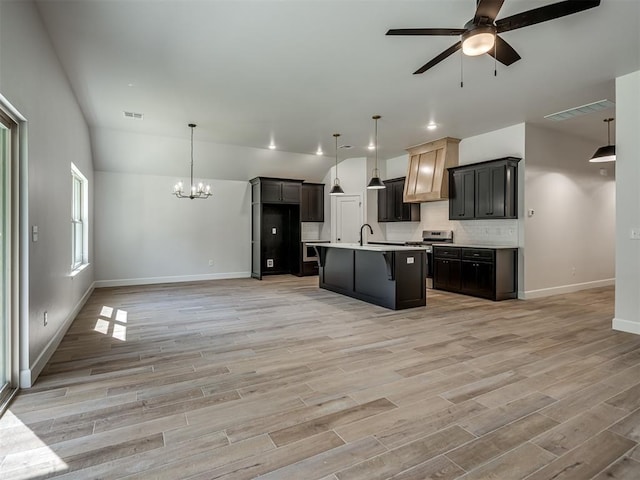 kitchen featuring a kitchen island with sink, decorative light fixtures, and light wood-type flooring