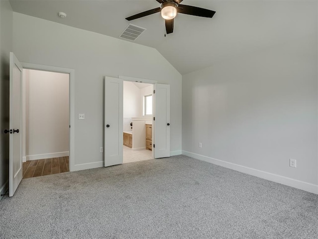 unfurnished bedroom featuring ceiling fan, light carpet, connected bathroom, and vaulted ceiling