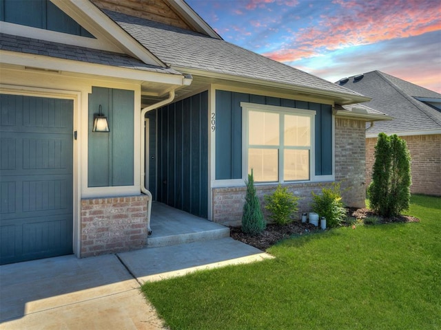 exterior entry at dusk featuring a lawn