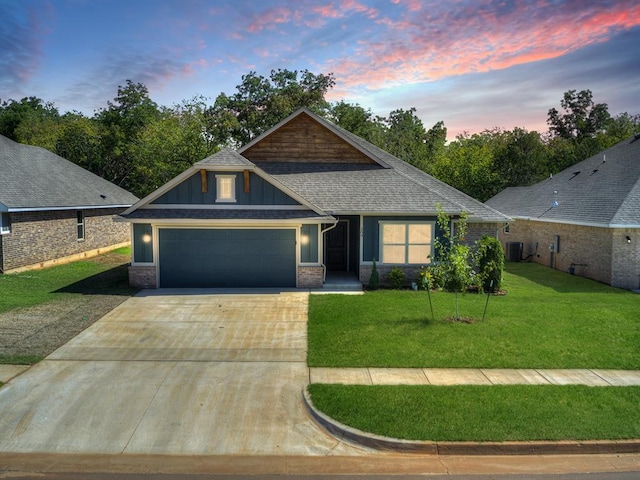 view of front of home featuring a lawn, central AC unit, and a garage