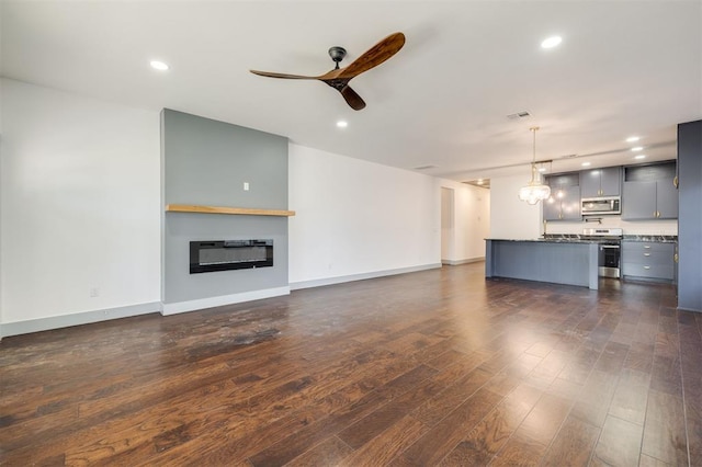 unfurnished living room featuring heating unit, ceiling fan, and dark hardwood / wood-style flooring