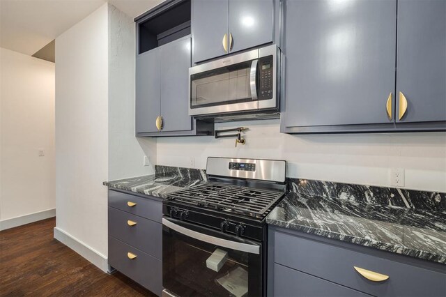 kitchen featuring dark stone counters, stainless steel appliances, and dark hardwood / wood-style floors