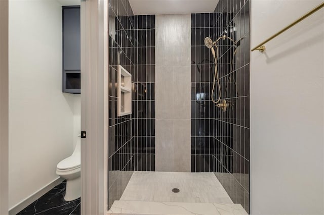 bathroom with a tile shower and toilet