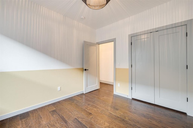 unfurnished bedroom featuring a closet and dark wood-type flooring