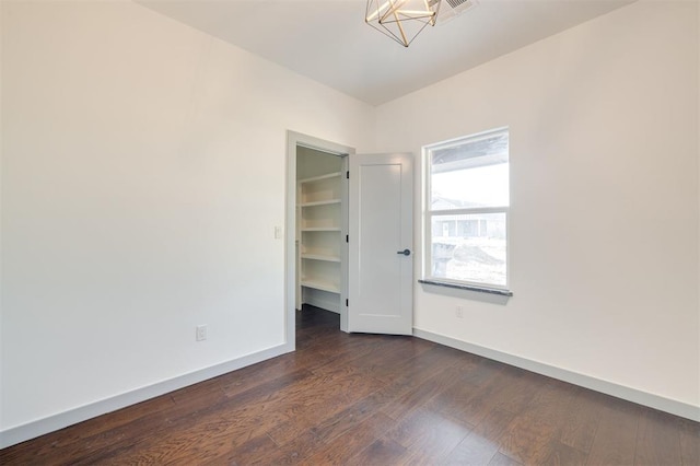 unfurnished bedroom with a walk in closet and dark wood-type flooring