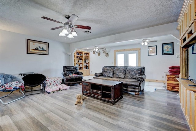 living room with french doors, light wood-type flooring, a textured ceiling, and ceiling fan