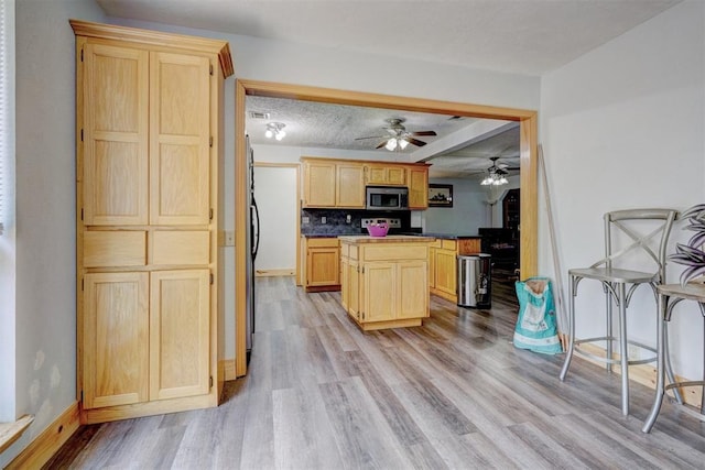 kitchen featuring ceiling fan, light hardwood / wood-style floors, a textured ceiling, decorative backsplash, and light brown cabinetry