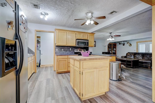 kitchen featuring light hardwood / wood-style flooring, a textured ceiling, light brown cabinetry, a kitchen island, and stainless steel appliances