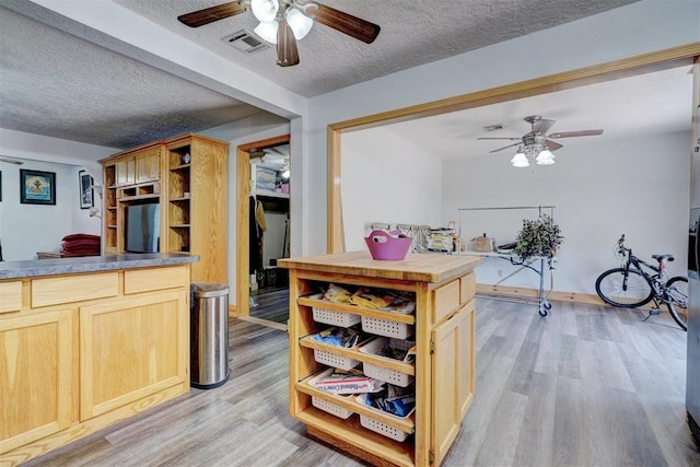 kitchen with light brown cabinets, light wood-type flooring, and a textured ceiling