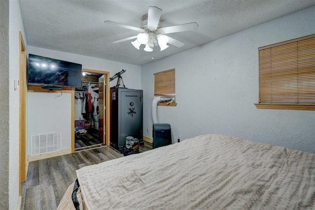 bedroom featuring ceiling fan, a spacious closet, dark hardwood / wood-style flooring, a textured ceiling, and a closet