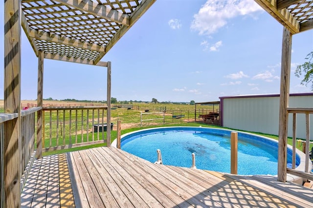 view of swimming pool featuring a pergola, a rural view, and a wooden deck