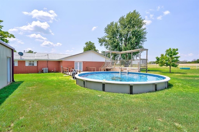 view of pool featuring a yard, central AC unit, and a deck