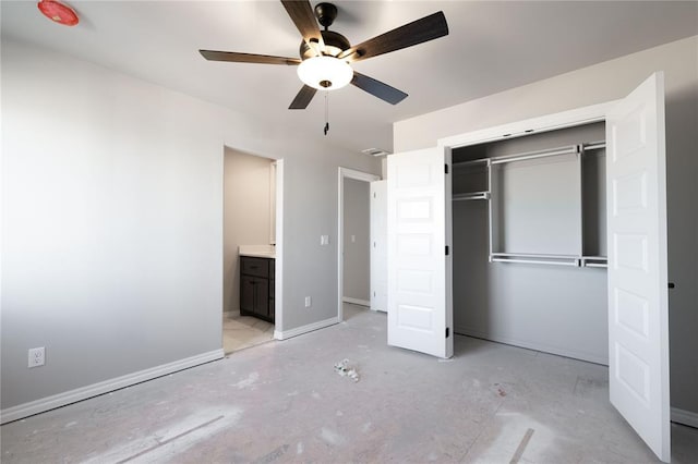 unfurnished bedroom featuring ceiling fan, connected bathroom, a barn door, and a closet