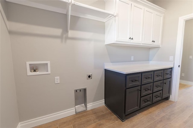 clothes washing area with electric dryer hookup, washer hookup, cabinets, and light wood-type flooring