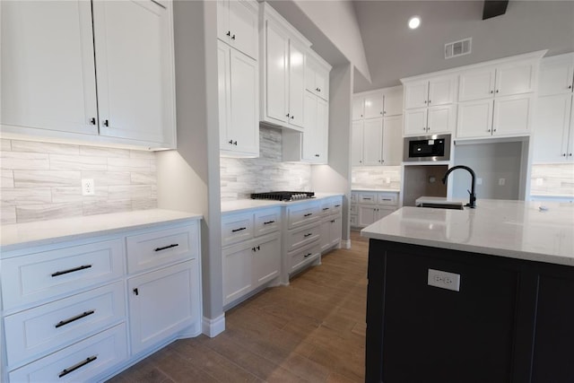 kitchen with sink, white cabinetry, dark hardwood / wood-style floors, stainless steel microwave, and light stone countertops