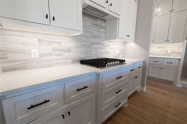 kitchen with stainless steel gas stovetop, white cabinetry, backsplash, and dark hardwood / wood-style flooring