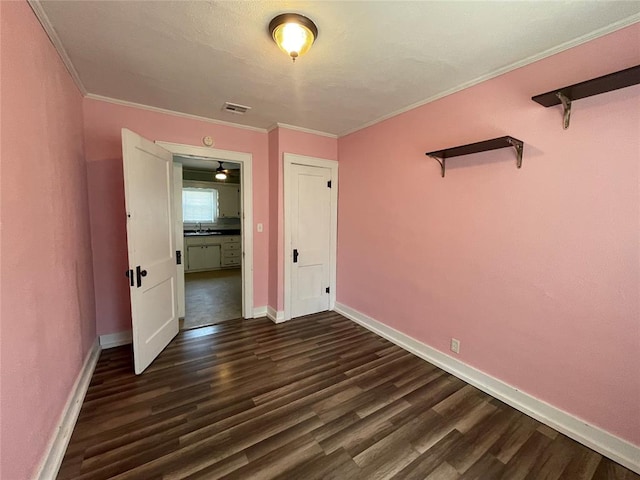 unfurnished bedroom featuring crown molding and dark wood-type flooring