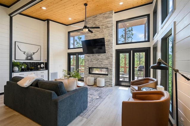 living room with a towering ceiling, light hardwood / wood-style flooring, plenty of natural light, and wooden ceiling