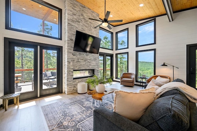 sunroom featuring vaulted ceiling with beams, ceiling fan, a stone fireplace, and wooden ceiling