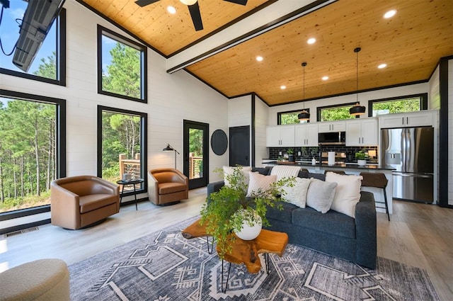 living room with a wealth of natural light, high vaulted ceiling, wooden ceiling, and light wood-type flooring