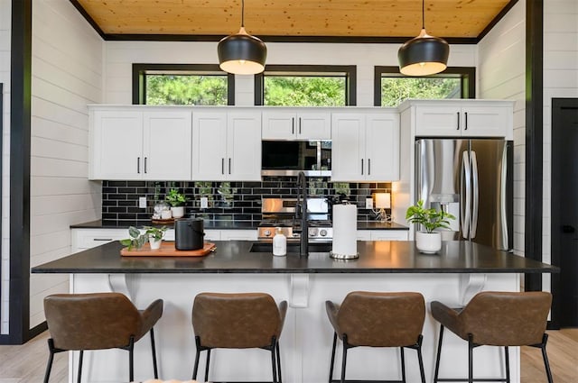 kitchen with pendant lighting, light hardwood / wood-style floors, white cabinetry, and appliances with stainless steel finishes