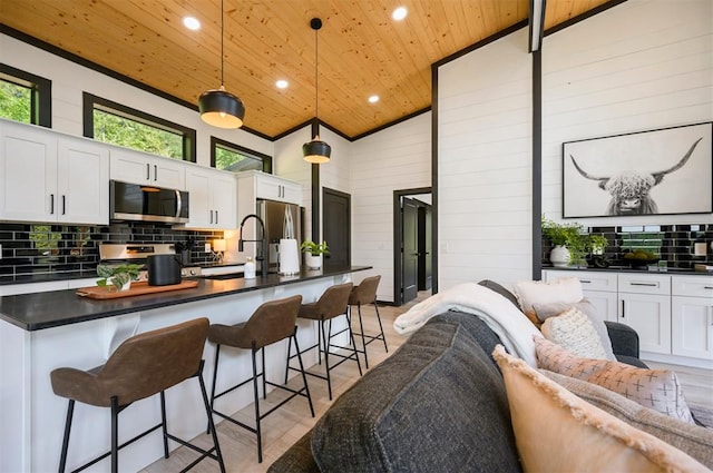 kitchen featuring high vaulted ceiling, white cabinets, hanging light fixtures, wood ceiling, and stainless steel appliances