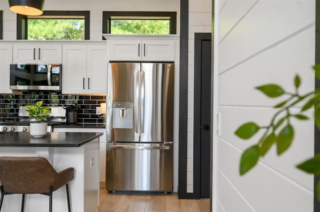 kitchen with white cabinets, a kitchen breakfast bar, light wood-type flooring, and appliances with stainless steel finishes