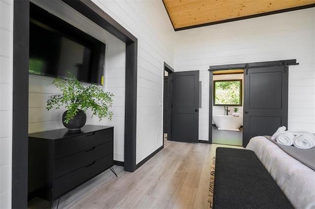 bedroom with wooden ceiling, a barn door, vaulted ceiling, and light hardwood / wood-style flooring