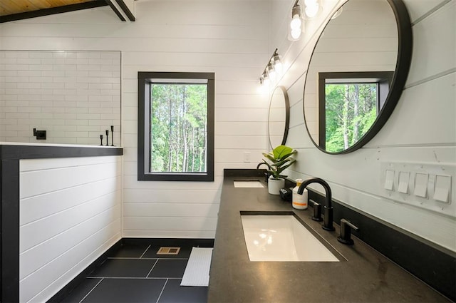 bathroom featuring wood walls, tile patterned flooring, vanity, and lofted ceiling