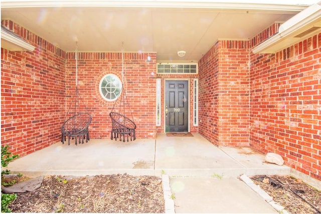 view of exterior entry with a patio area