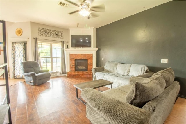 living room featuring ceiling fan, light hardwood / wood-style floors, and a fireplace