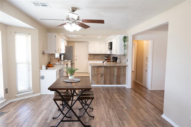 kitchen featuring backsplash, black range oven, sink, hardwood / wood-style floors, and white cabinetry