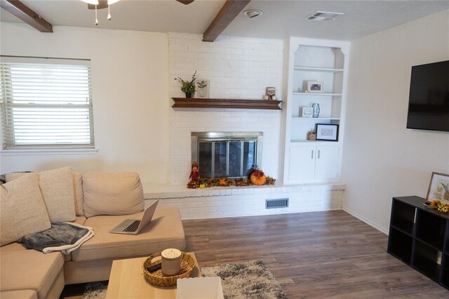 living room featuring beamed ceiling, dark hardwood / wood-style floors, and a brick fireplace