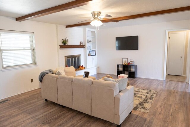 living room with beam ceiling, a large fireplace, ceiling fan, and hardwood / wood-style floors