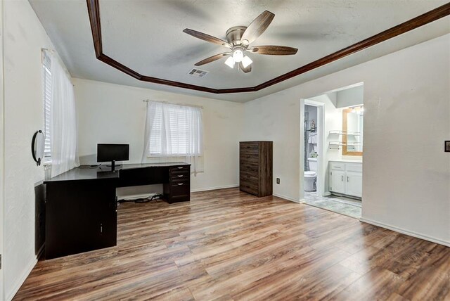 office space with a tray ceiling, ceiling fan, light hardwood / wood-style flooring, and crown molding