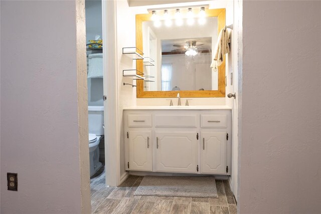 bathroom with ceiling fan, hardwood / wood-style floors, vanity, and toilet