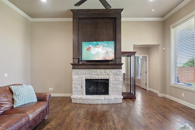 living room with a stone fireplace, ceiling fan, dark hardwood / wood-style floors, and ornamental molding