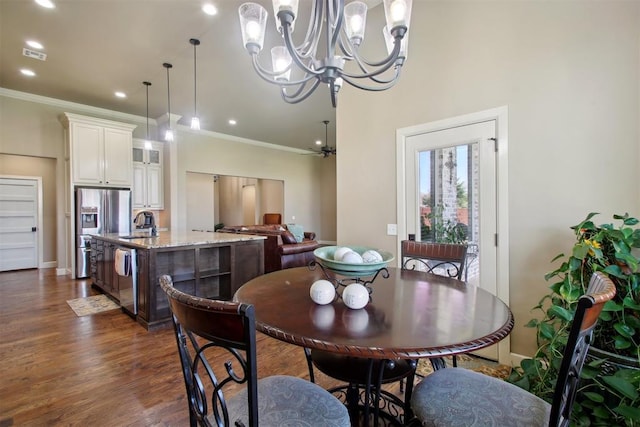 dining area featuring sink, ceiling fan with notable chandelier, crown molding, and dark wood-type flooring