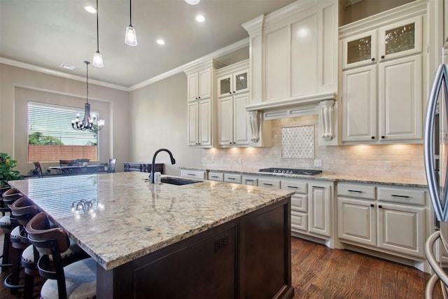 kitchen featuring a kitchen island with sink, sink, white cabinets, and stainless steel gas stovetop