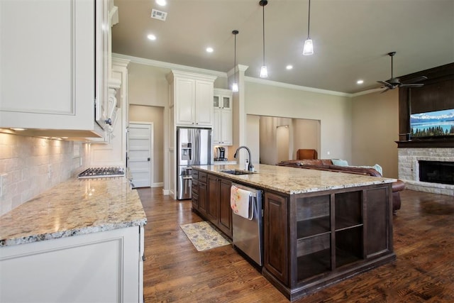 kitchen with dark brown cabinetry, dark hardwood / wood-style floors, a fireplace, a center island with sink, and appliances with stainless steel finishes