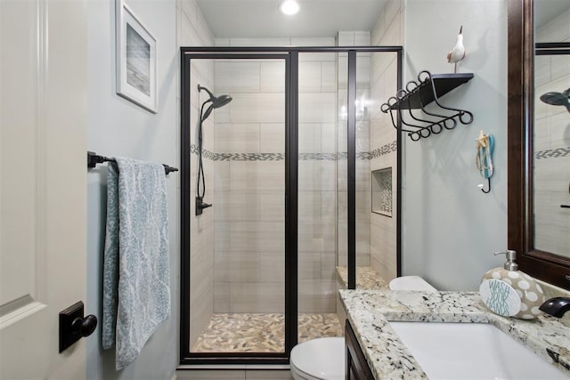 bathroom featuring vanity, an enclosed shower, and toilet