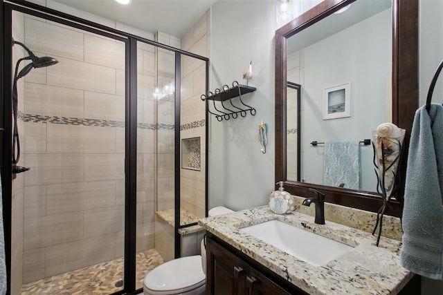 bathroom featuring vanity, toilet, and a shower with shower door