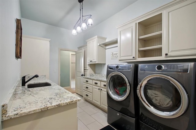 clothes washing area with washer and clothes dryer, sink, cabinets, and an inviting chandelier