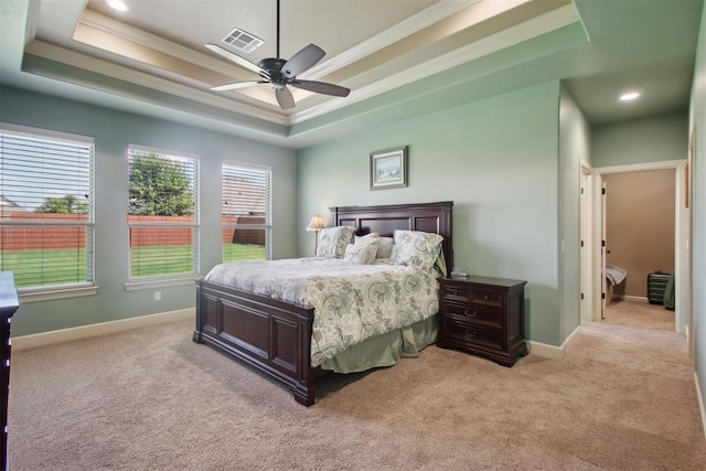 bedroom with ornamental molding, light colored carpet, ceiling fan, and a tray ceiling