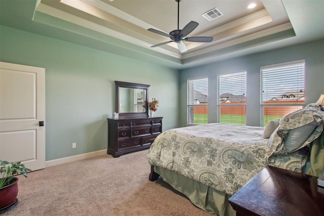 bedroom with a raised ceiling, ceiling fan, light colored carpet, and ornamental molding