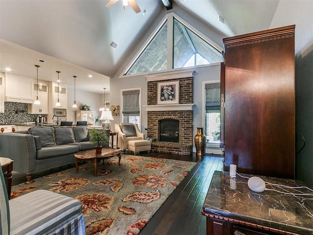 living room with a brick fireplace, high vaulted ceiling, plenty of natural light, and dark wood-type flooring