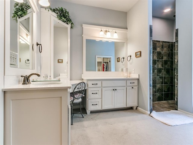 bathroom with a tile shower and vanity